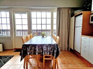 a dining room table with chairs and a kitchen with windows at Apartment Kehtola, Tahkovuori in Kuopio