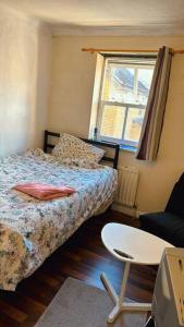 a bedroom with a bed and a chair and a window at Spacious,warm room in London in Mitcham