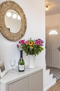 - une bouteille de vin et des fleurs sur une commode avec un miroir dans l'établissement Lovely House - Near Paris and Orly Airport, à Juvisy-sur-Orge
