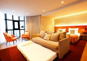 Montebelo Viseu Congress Hotel في فيزيو: غرفة في الفندق مع أريكة وسرير