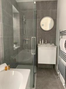 a bathroom with a shower and a tub and a sink at Jurassic Hideaway in Budleigh Salterton