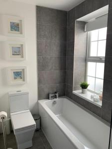 a bathroom with a tub and a toilet and a window at Jurassic Hideaway in Budleigh Salterton