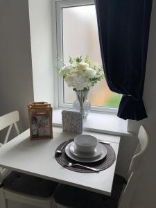 a white table with a vase of flowers and a window at Jurassic Hideaway in Budleigh Salterton