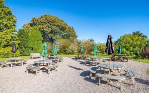 un grupo de mesas de picnic y sombrillas en un parque en The Brantwood Hotel en Penrith