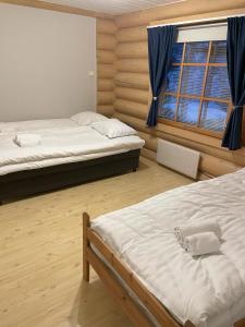 een slaapkamer met 2 bedden en een raam bij Log home near Santa in Rovaniemi
