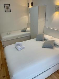 um quarto com 2 camas e lençóis brancos em Apartamento Pensamento Inédito 55 em Lisboa