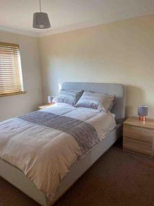 a bedroom with a bed and a night stand with a lamp at Stornoway Holiday Let in Stornoway