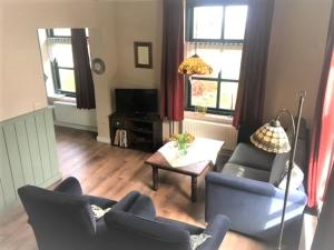 a living room with two blue chairs and a table at Droomboerderijtje in Merselo