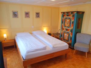 a bedroom with a large bed and a chair at Adler Hotel in Appenzell