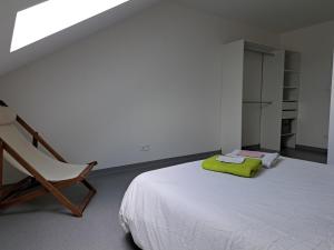 a white bedroom with a bed and a chair at Appartement proche centre ville et sur les remparts in Langres