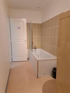a bathroom with a white tub and a white door at Appartement proche centre ville et sur les remparts in Langres