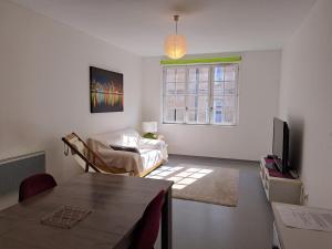 a living room with a couch and a tv and a table at Appartement proche centre ville et sur les remparts in Langres