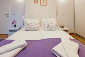 a large white bed with pillows and a purple rug at Apartment Vijećnica in Sarajevo