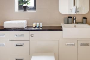 La salle de bains blanche est pourvue d'un lavabo et d'un miroir. dans l'établissement Charming Two-Bedroom Retreat in Morden SM4, London, à Morden