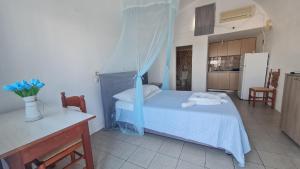 a bedroom with a blue bed and a kitchen at Zacharo Studios Thirasia in Therasia