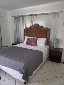 a bedroom with a large bed with a wooden headboard at Sunset condos getaway In Ocho Rios in Ocho Rios