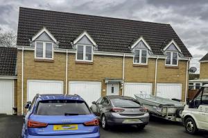 a house with two cars parked in a parking lot at K Suites - Shetland Court in Bridgwater