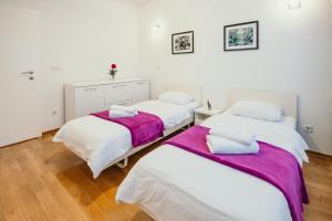 3 łóżka w pokoju z białymi ścianami i drewnianą podłogą w obiekcie Apartment Vijećnica w Sarajewie