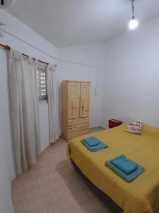 Un dormitorio con una cama amarilla con toallas azules. en Departamento en Paraná