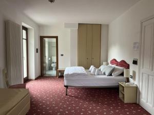 um quarto com uma grande cama branca e uma casa de banho em Hotel Lido em Ledro