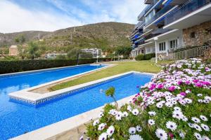 a swimming pool with flowers in front of a building at Apartamento Reisol in Castelldefels
