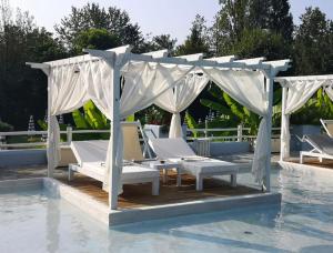 a group of lounge chairs under a canopy over a pool at Villa Chicca in Neviano degli Arduini
