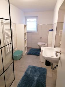 y baño con lavabo, aseo y alfombras azules. en Fewo Halbe Tanne, en Schonach