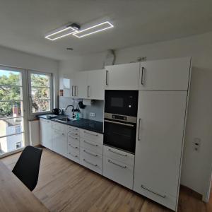 La cuisine est équipée de placards blancs et d'un réfrigérateur blanc. dans l'établissement City Apartments Offenbach, à Offenbach-sur-le-Main