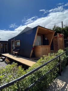 a tiny house with a wooden porch and a deck at Viento Sur Pichilemu Tiny House con Mini Parrilla y opción de Hot Tub in Pichilemu