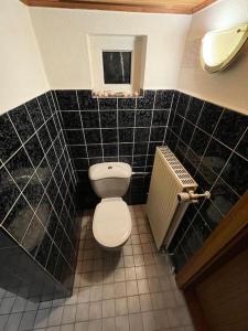 a bathroom with a white toilet and black tiled walls at Sleep Point Bremermann in Bremen