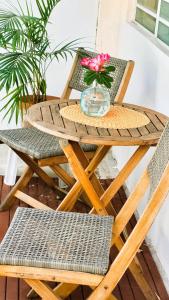 einen Holztisch mit einer Schüssel Blumen und zwei Stühlen in der Unterkunft Cozy Beach Apartment in San Juan