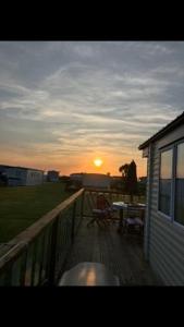 a sunset on the deck of a house at Cosy caravan Sunbeach in Llwyngwril