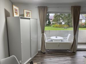バート・ローテンフェルデにある1 Zimmer Appartement in Bad Rothenfeldeのテーブルと椅子、大きな窓が備わる客室です。