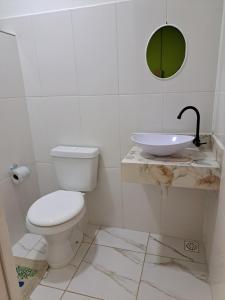 a bathroom with a white toilet and a sink at Girassol Hostel by Katita in Paraty