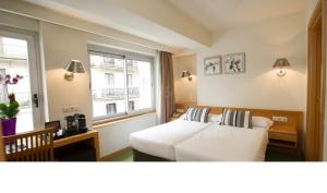 a hotel room with a bed and two windows at Hotel Zaragoza Plaza in Donostia-San Sebastián