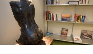 a statue of a woman sitting on a table next to a book shelf at Hotel Zaragoza Plaza in Donostia-San Sebastián