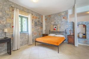 a bedroom with a bed and a stone wall at Luxury Villa Nefeli in Stoupa, Private Pool & BBQ in Neokhórion