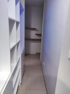 um closet com prateleiras brancas e piso em azulejo em Conde Hotel Piura em Piura