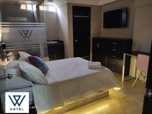 um quarto de hotel com uma cama com almofadas e uma televisão em W Hotel em Pasaje
