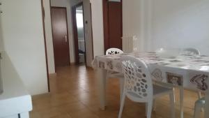 a dining room table with white chairs and a white table cloth at STELLA appartamento in Policoro +16 photos