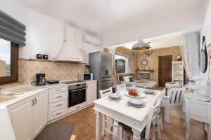 a kitchen with white cabinets and a table and chairs at Evi's Afandou Suite in Afantou