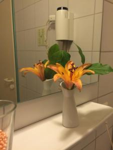 a vase with flowers on a counter in a bathroom at Hotel Ragusa in Dormagen