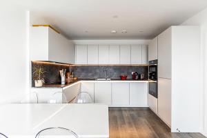 una cocina blanca con armarios y electrodomésticos blancos en Charming West London Nest, en Londres