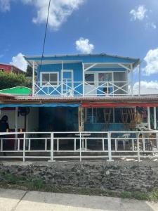 a blue house with a white fence in front of it at Baba’s Beach Bungalow in Providencia