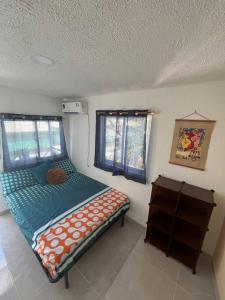 a small bedroom with a bed and two windows at Baba’s Beach Bungalow in Providencia