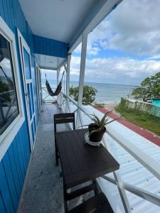 a table and chairs on a porch with the ocean at Baba’s Beach Bungalow in Providencia