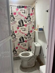 a bathroom with a toilet and a shower curtain at Baba’s Beach Bungalow in Providencia