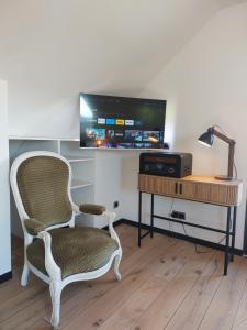 Zimmer mit einem Stuhl und einem Schreibtisch mit einem TV in der Unterkunft Gite les Caravottes 4 Etoiles avec Jacuzzi - JURA in Courlaoux