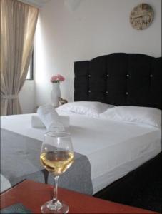 - un verre de vin assis sur une table à côté d'un lit dans l'établissement HOTEL DINASTIA REAL NEIVA, à Neiva