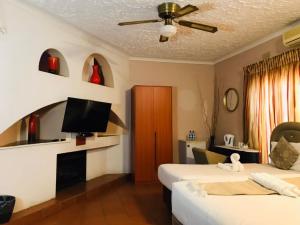 a hotel room with two beds and a flat screen tv at Inca Rose Guest House in Francistown